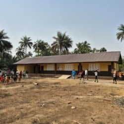 Schoolgebouw met palmbomen en kinderen in een ontwikkelingsland.
