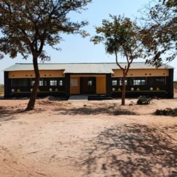 Huis in Phawa met omheining, bomen en zandgrond, impact van vrijwilligers zichtbaar.