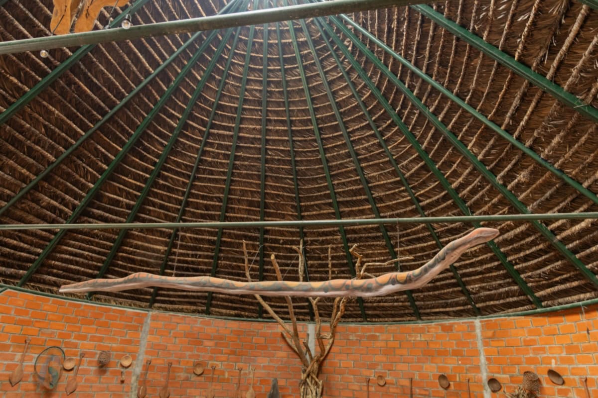 Interieur van de gemeenschapsruimte Sinchi Warmi met rieten dak en decoratieve elementen.