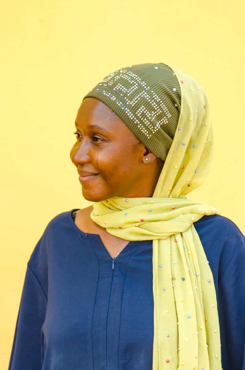 Vrouw met hoofddoek die glimlacht, vrijwilligerswerk in Afrika.