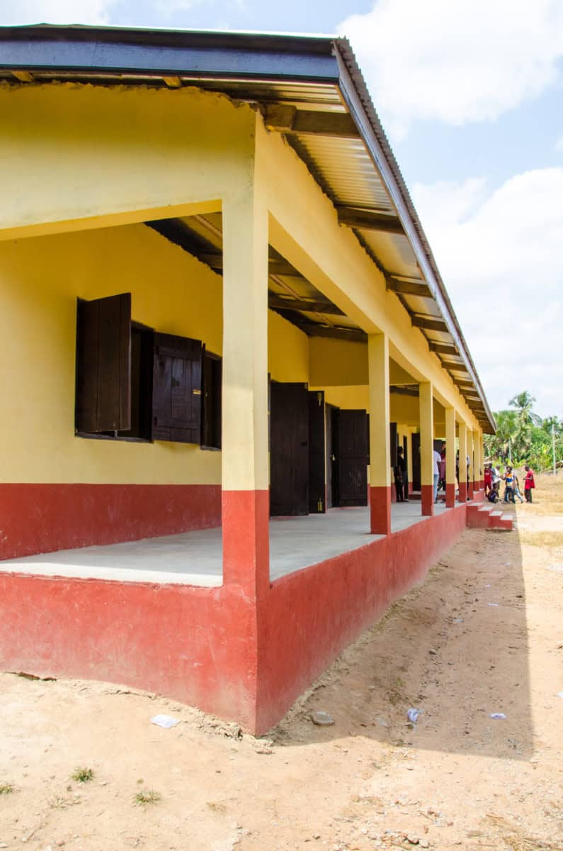 Schoolgebouw in Kokosiase met open deuren en leerlingen in de achtergrond.