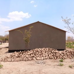 Gebouw in ontwikkelingsgebied met stapel bakstenen, klaar voor gebruik.