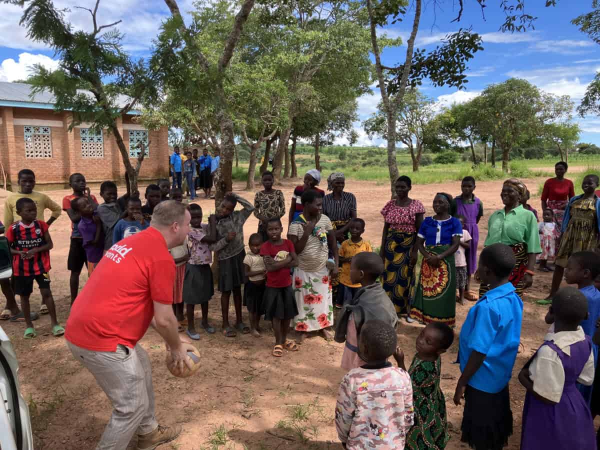 Vrijwilliger speelt met kinderen in Kaviwale, Malawi, tijdens bouwproject.