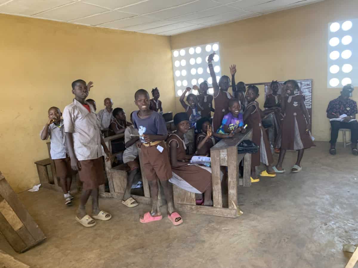Kinderen in een klaslokaal in Guinnee met zonlicht door de ramen.